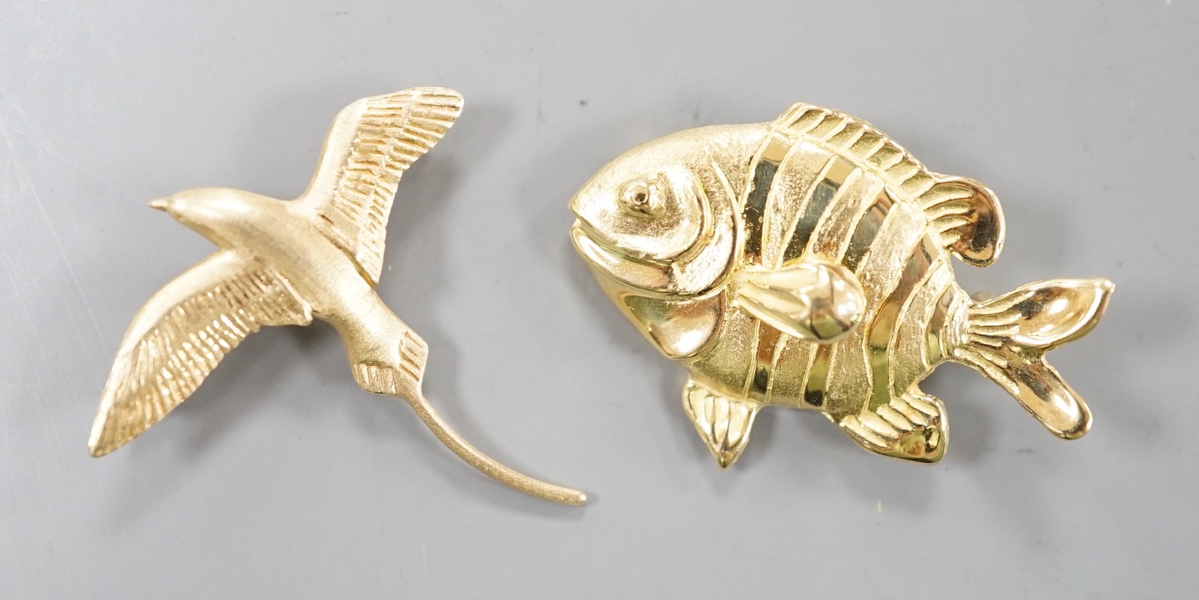 A 14k yellow metal bird brooch modelled as a Bermuda Longtail, 31mm, 2.9 grams and an Astwood Dickenson 18ct fish pendant brooch, 6.5 grams.